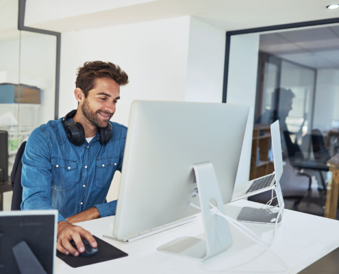 Side View Of Man Typing On Computer And Smiling