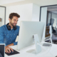 Side View Of Man Typing On Computer And Smiling