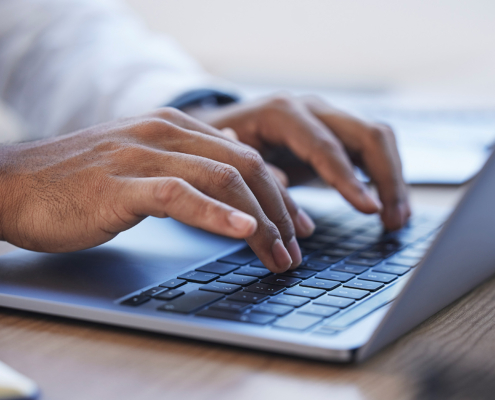 Side View Of Hands Typing On Computer