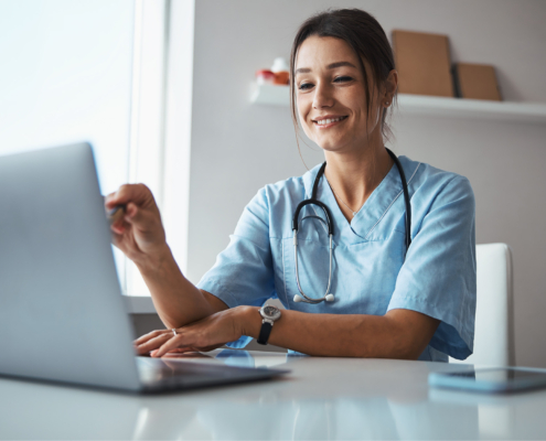 Charming Female Doctor Using Modern Laptop At Work