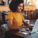 Young Woman In Café Typing On Laptop