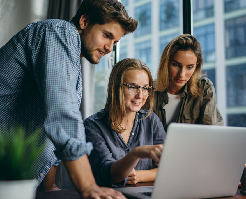 Side View Of Three Coworkers Looking At Laptop
