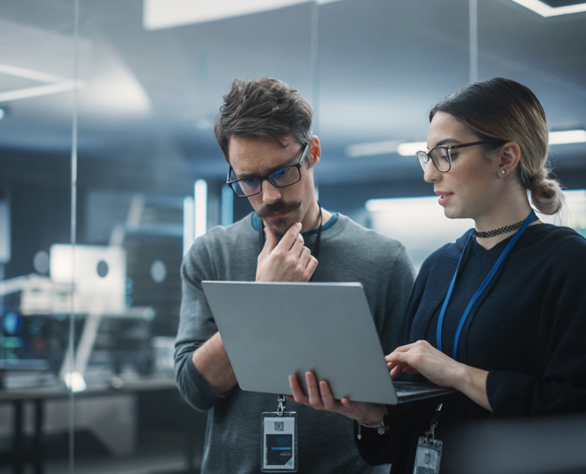 Side View Of Two Cybersecurity Professionals Looking At Laptop