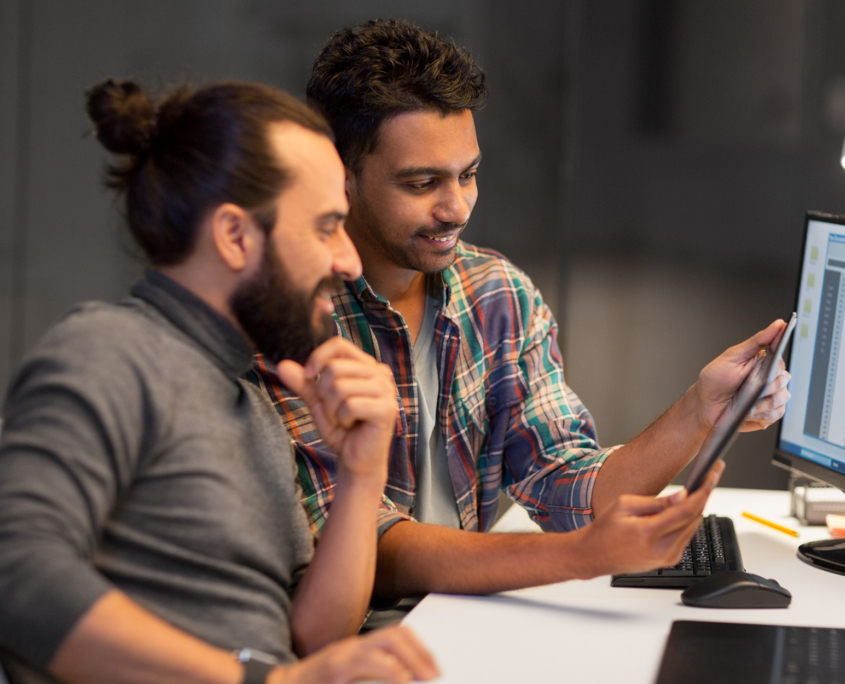 Side View Of Two Happy Men Looking At Tablet