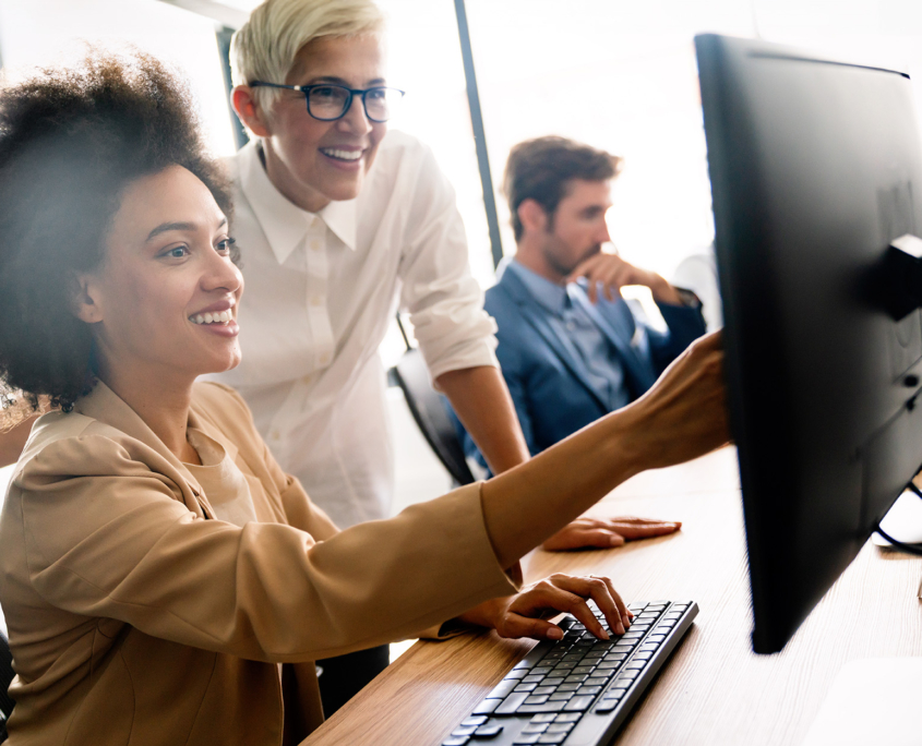 Side View Of Two Women Looking At Computer Smiling